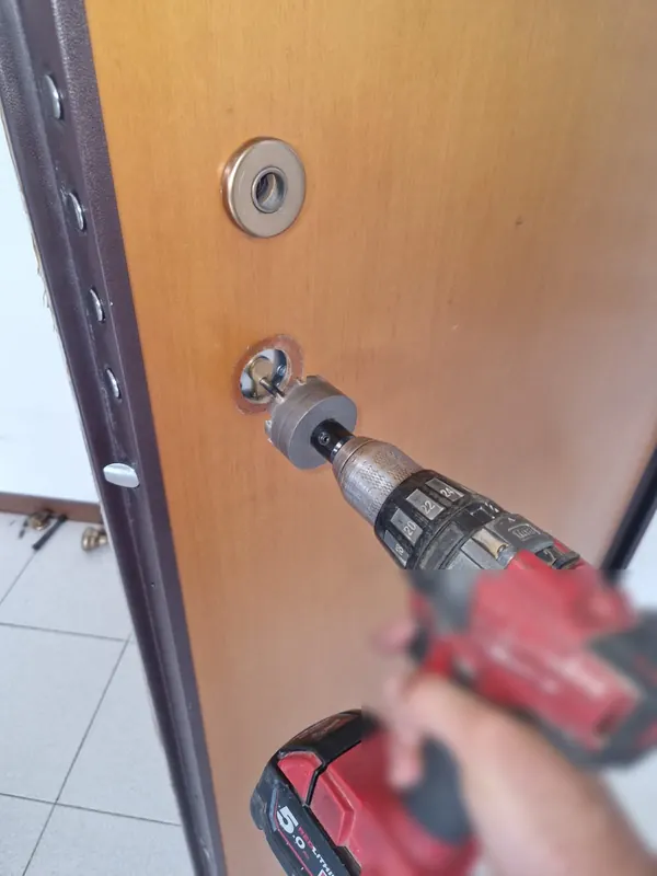 Fabbro al lavoro sul cilindro di una porta blindata a Bologna